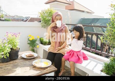 muslimische Frau und Kinder Frühstück zu Hause auf dem Dachgarten Stockfoto