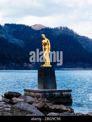 Eine goldene Statue von Tatsuko steht gegen das majestätische Wasser des Tazawa Sees. Stockfoto