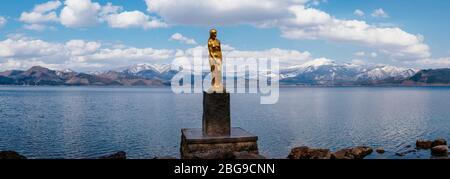 Eine goldene Statue von Tatsuko steht gegen das majestätische Wasser des Tazawa Sees. Stockfoto