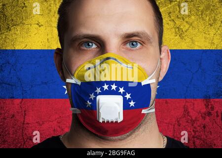 Junger Mann mit Wunden Augen in einer medizinischen Maske in den Farben der Nationalflagge von Venezuela gemalt. Coronovirus-Krankheit COVID-19 Konzept. Der Mensch ist afr Stockfoto