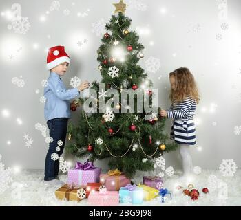 Kinder schmücken Weihnachtsbaum mit Kugeln im Zimmer Stockfoto