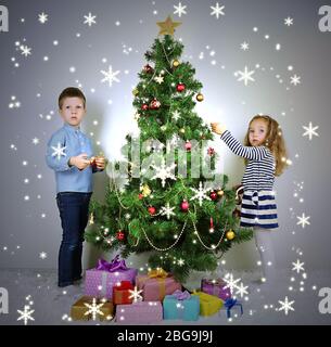 Kinder schmücken Weihnachtsbaum mit Kugeln im Zimmer Stockfoto