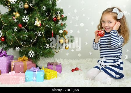 Kleines Mädchen schmücken Weihnachtsbaum mit Kugeln im Zimmer Stockfoto