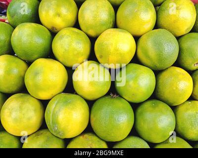 Verkauf saftig frisch grüne Orangen Nahaufnahme. Großhandelsmarkt. Grüne Orangen in einer Box. Verkauf von Feldfrüchten auf dem Markt. Natürliche, gesunde, vitaminreiche Lebensmittel Stockfoto