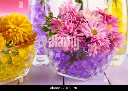 Schöne Blumen in Vasen mit Hydrogel auf dem Tisch aus nächster Nähe Stockfoto