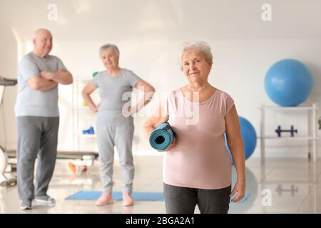 Ältere Frau mit Yogamatte im Fitnessstudio Stockfoto
