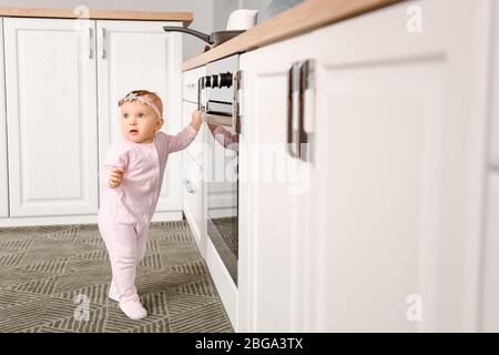 Kleines Baby in der Nähe Herd in der Küche. Kind in Gefahr Stockfoto