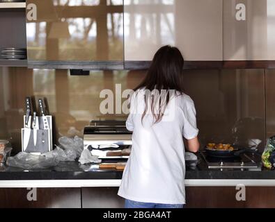 Eine Frau mit dunklen langen Haaren Kochen in einer modernen Küche Stockfoto