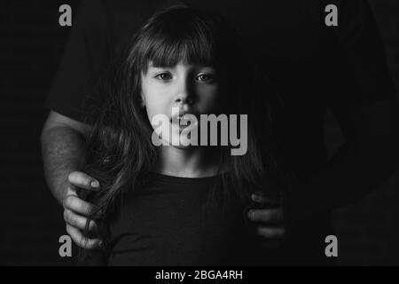 Vater mit seiner kleinen Tochter auf dunklem Hintergrund. Konzept der häuslichen Gewalt Stockfoto