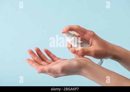Ansicht der Frau, die Sprühflasche mit Handdesinfektionsmittel auf Blau isoliert hält Stockfoto