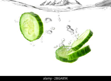 Fallen von frischen Gurkenscheiben in Wasser vor weißem Hintergrund Stockfoto