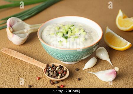 Köstliche Joghurt-Sauce mit Gurke in Schüssel auf farbigen Hintergrund Stockfoto