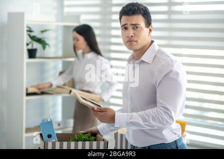 Aufgeregt junge Brünette männlich stehen an seinem Schreibtisch Stockfoto