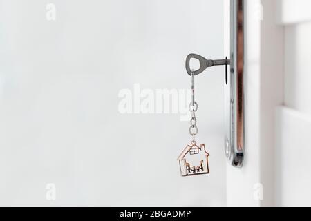 Geöffnete Tür mit Schlüssel und Schlüsselanhänger aus Metall in Hausform. Tür zu einem neuen Haus. Echter Markt im Osten. Familienkonzept. Stockfoto