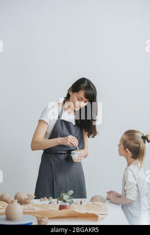 Potter Frau erzählt ihrem kleinen Lehrling von ihrem Charakterzug Stockfoto