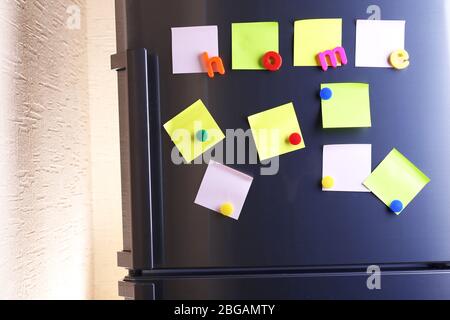 Leere Papierblätter und bunte Magnete an der Kühlschranktür Stockfoto