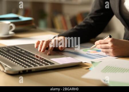 Nahaufnahme von Unternehmerin Hände Vergleich Graph Bericht auf Laptop in der Nacht Stockfoto