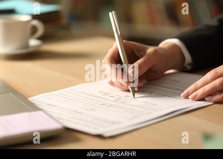 Nahaufnahme der Unternehmerin Hände Ausfüllen Formular Check ja in der Nacht auf einem Schreibtisch Stockfoto