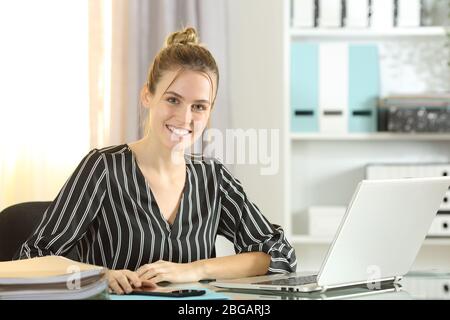 Glückliche Unternehmerin mit Laptop, die Kamera auf einem Schreibtisch im Homeoffice sitzt Stockfoto