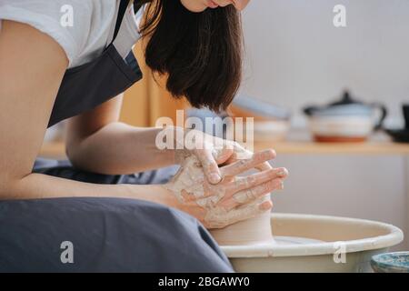 Nahaufnahme einer Frau, die in ihrer privaten Werkstatt eine Tonvase auf einem Töpferrad formt Stockfoto