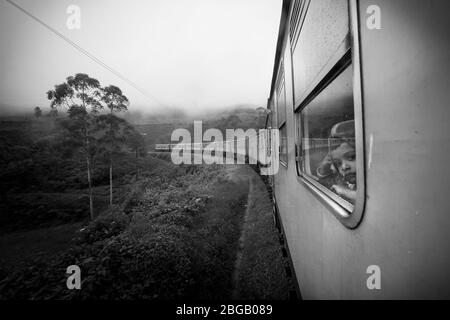 Nuwara Eliya, Sri Lanka. 26. Juli 2016: Ein Kind schaut aus dem Fenster in den Zug, der die Natur und die Teeplantagen in Nuwara Eliya i durchquert Stockfoto