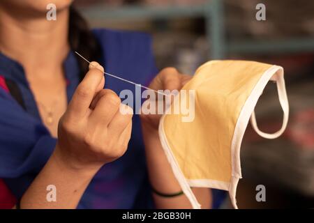 Nahaufnahme von Mädchen Hand Stricken DIY Gesichtsmaske zu Hause vor Covid-19 oder Coronavirus Pandemie in Indien zu schützen - aufgrund des Mangels an medizinischen Masken Frau Stockfoto