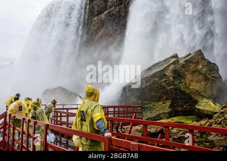 Niagara Falls, NY, USA - 13. Juni 2019: Besucher in Regenmänteln auf nassen Holztreppen gehen unter den Spritzern der American Falls auf Tour Stockfoto