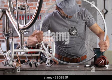 Mann reparieren das Vintage-Fahrrad in der Werkstatt auf der Werkbank mit Werkzeugen, diy-Konzept Stockfoto