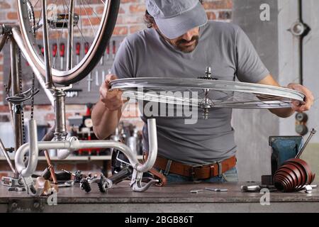 Mann reparieren das Vintage-Fahrrad in der Werkstatt auf der Werkbank mit Werkzeugen, diy-Konzept Stockfoto