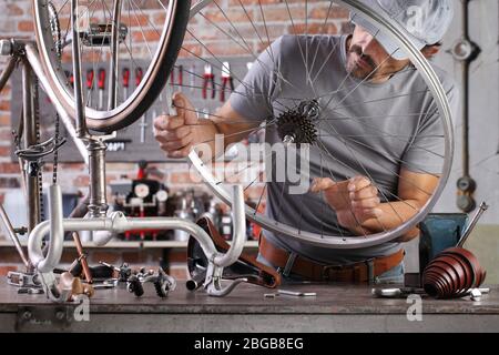Mann reparieren das Vintage-Fahrrad in der Werkstatt auf der Werkbank mit Werkzeugen, diy-Konzept Stockfoto