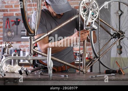 Mann reparieren das Vintage-Fahrrad in der Werkstatt auf der Werkbank mit Werkzeugen, diy-Konzept Stockfoto