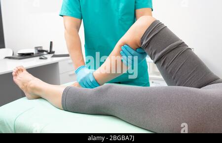 Physiotherapeut überprüft das Bein des Patienten in der Traumaabteilung der Klinik. Nahaufnahme des verletzten Beinbeins des Patienten Stockfoto