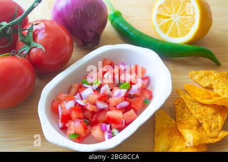 Mexikanische Salsa Pico de gallo mit Tomaten, roten Zwiebeln, würzigen grünen Jalapeno Pfeffer, Zitrone und Nacho Mais-Chips Stockfoto