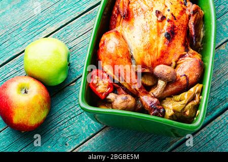 Gebackenes Huhn mit Äpfeln auf altem Holztisch.Gebratenes Huhn mit Äpfeln.schmackhaftes aromatisches Rotisserie-Huhn Stockfoto