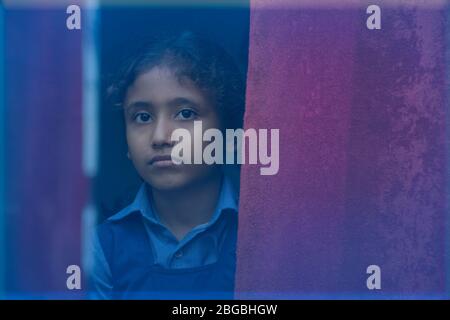 Schulmädchen schaut durch Fenster Stockfoto