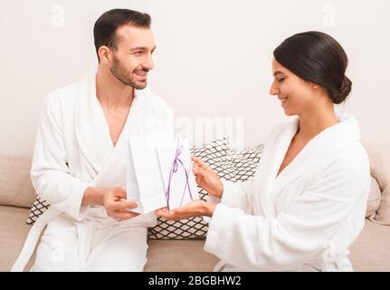 Schönes Paar ist sehr glücklich mit einem Geschenk aus dem Spa Salon Zertifikat für Besuche in Massage und Sauna. Mann und Frau tragen in Bademäntel halten Stockfoto