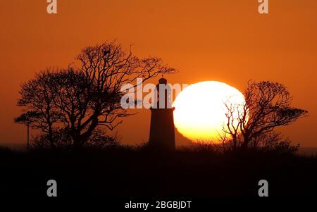 Die Sonne geht hinter dem St Mary's Lighthouse in der Nähe von Whitley Bay, Northumberland, auf. Stockfoto