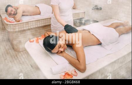 Gemischte Rasse Frau mit Haut Peeling in türkischen Hammam, während ihr Freund genießt die Wärme eines türkischen Bad Marmor Massageliege Stockfoto