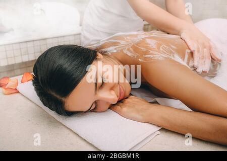 Hammam. Masseur Anwendung Schaum auf eine schöne Frau auf den Körper. Frau entspannt in einem Hammam Stockfoto