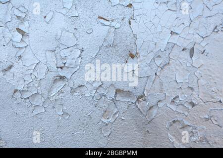 Die Textur der alten gemalten Wand ist mit Rissen und Rauheit Nahaufnahme bedeckt. Stock Foto von alter Farbe mit Rissen. Farbe Silber, Chrom Farbe. Stockfoto