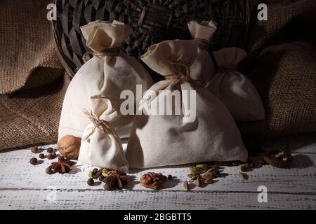 Säcke voll mit Gewürzen, auf Holztisch, auf Sack-Hintergrund Stockfoto