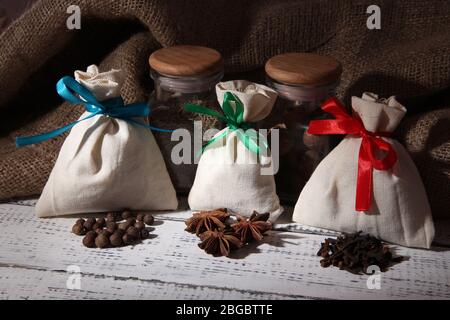 Säcke und Gläser voll mit Gewürzen, auf Holztisch, auf Sacktuch Hintergrund Stockfoto