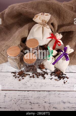 Säcke und Gläser voll mit Gewürzen, auf Holztisch, auf Sacktuch Hintergrund Stockfoto