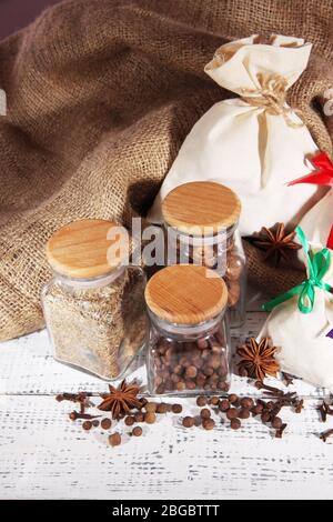 Säcke und Gläser voll mit Gewürzen, auf Holztisch, auf Sacktuch Hintergrund Stockfoto