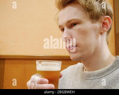 Ein schöner junger Mann, der sein Bier genießt Stockfoto