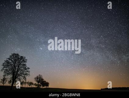 Petersdorf, Deutschland. April 2020. Der Sternenhimmel scheint nachts über die Landschaft. Meist sternenklare Himmel ermöglichen einen ungehinderten Blick auf die Sternschnuppen der Lyrides in der kommenden Nacht. Die Erde kreuzt den Schweif eines Kometen. Dies wurde 1861 im Sonnensystem entdeckt. Jedes Jahr um den 21., 22., 23. April, überquert die Erde den Rest des Kometenschweifs. Dabei gelangen Staubpartikel in die Erdatmosphäre. Diese Partikel brennen auf den Aufprall und Sternschnuppen werden sichtbar. Quelle: Patrick Pleul/dpa-Zentralbild/dpa/Alamy Live News Stockfoto