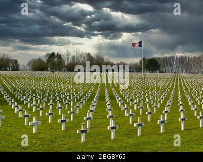 Vor dem dunklen, bedrohlichen Himmel Reihen von Gräbern von Soldaten des 1. Weltkriegs, die durch weiße Kreuze auf dem Friedhof La Targette bei Arras in Nordfrankreich markiert sind. Stockfoto