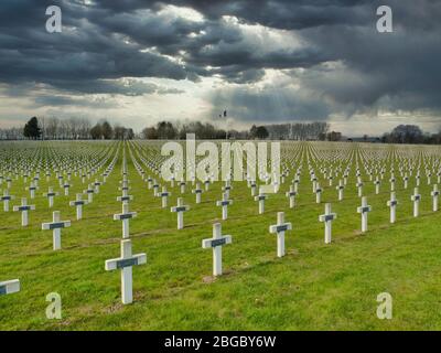 Vor dem dunklen, bedrohlichen Himmel Reihen von Gräbern von Soldaten des 1. Weltkriegs, die durch weiße Kreuze auf dem Friedhof La Targette bei Arras in Nordfrankreich markiert sind. Stockfoto