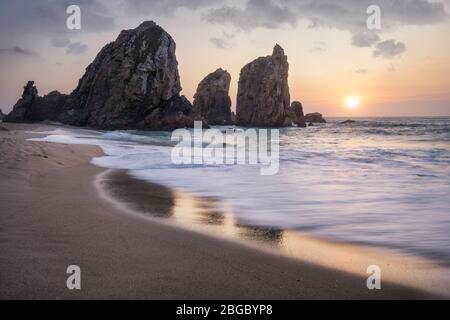 Portugal Ursa Beach. Das wunderschöne Meer stapelt Felsen im Sonnenuntergang Licht. Weiße atlantikwellen am leeren Sandstrand. Stockfoto