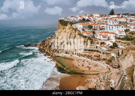 Urlaub vibes auf schönen Azenhas do Mar Dorf und Wellenschutz Strand. Weiße Kreidehäuser am Rand einer Klippe. Bly Himmel und weiße Wolken. Sintr Stockfoto